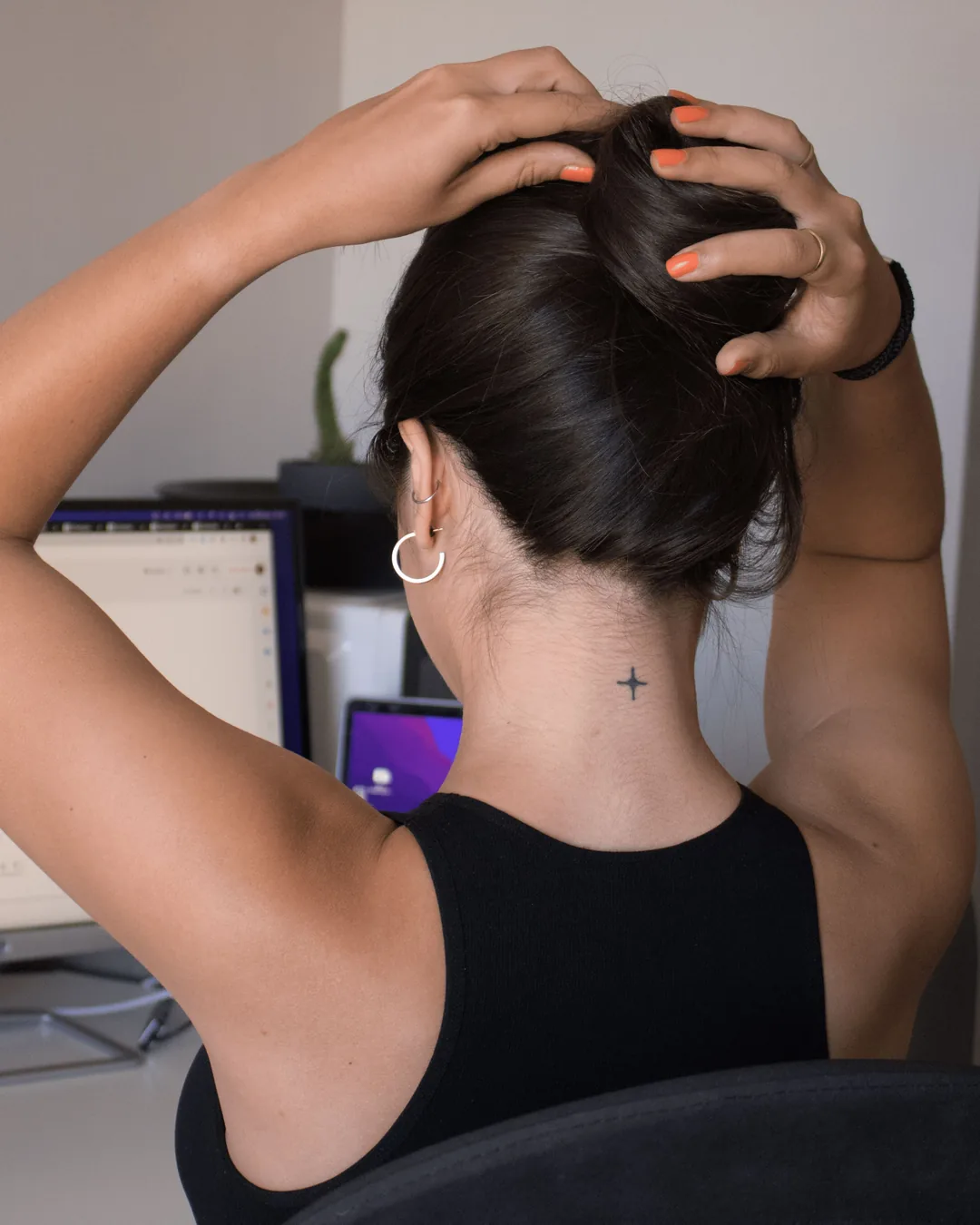 Une personne assise à son bureau, vue de dos, les mains sur la tête